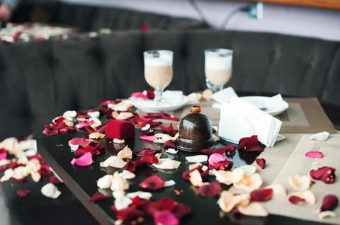 Two cups of coffee on a table strewn with petals. The guy just confessed his Stock Photos