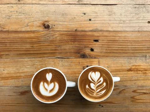 Two cups of different latte art hot coffee on brown beautiful pattern wood table Foto stock