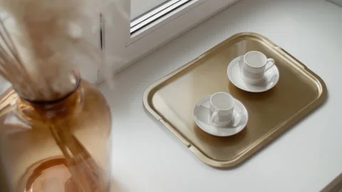 Two cups on a golden tray on the windowsill Stock Footage 170550172