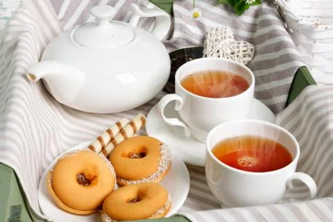 Two cups of hot tea with delicious cookies on white wooden table Stock Photos