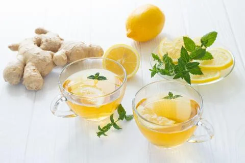 Two cups of hot tea with ginger, lemon and mint on a white wooden table Stock Photos