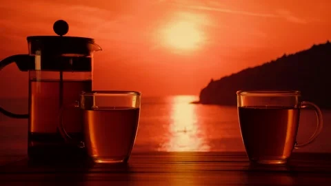 Two cups with hot tea on the table in front of the sea at sunset Stock Footage 139312896