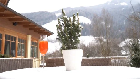Two cups of juice are placed on a snow-covered table as it snows in slow motion Video stock 127453559