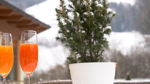 Two cups of juice are placed on a snow-covered table as it snows in slow motion Video stock 127453603