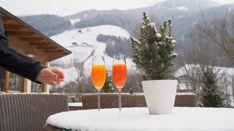 Two cups of juice are placed on a snow-covered table as it snows in slow motion Video stock 127453739