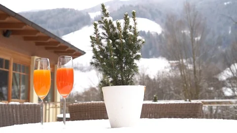 Two cups of juice are placed on a snow-covered table as it snows in slow motion Video stock 127453779