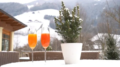 Two cups of juice are placed on a snow-covered table as it snows in slow motion Video stock 127453841