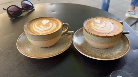 Two Cups Of Latte Art Coffee And Sunglasses On Outdoor Terrace Table Stock Footage 335903485