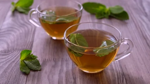 Two cups of mint herbal tea in transparent mugs on a wooden background Stock Footage 194507094