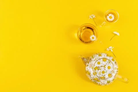 Two cups of tea and transparent teapot with camomile flowers on yellow backgr Foto stock