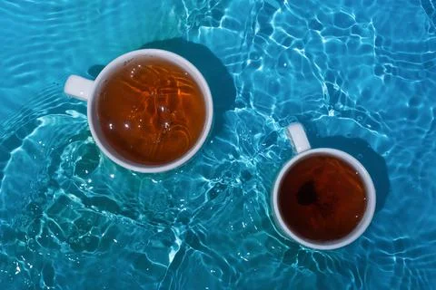 Two cups of tea in blue splashing water Stock Photos