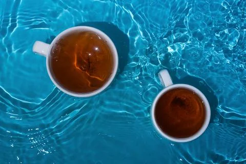 Two cups of tea in blue splashing water Stock Photos