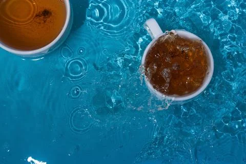 Two cups of tea in blue splashing water Stock Photos