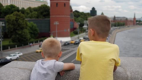 Two curious boys are standing on a bridge overlooking a busy city street. Stock Footage 311153825
