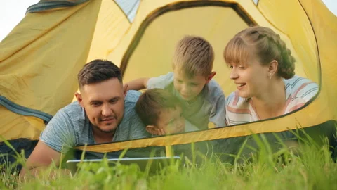 Two curious children playing with a tablet in outdoor next to their parents Stock Footage 121099804