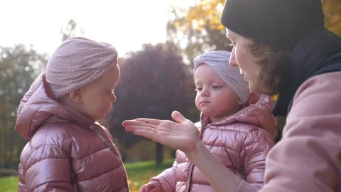 Two curious girls look at insect on mother's hand spending quality time in Stock Footage 144875424