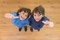The two curly twin thumb up to the camera. View from above Photo