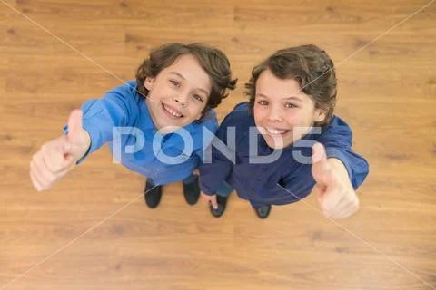 The two curly twin thumb up to the camera. View from above Stock Photos
