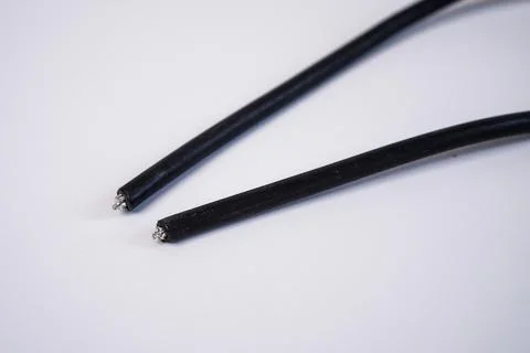 Two cut ends of a black electrical wire, exposing the inner metallic copper.. Stock Photos