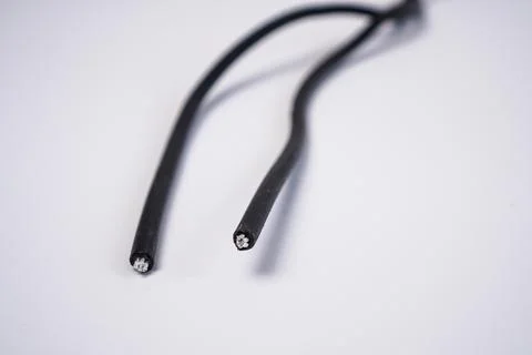 Two cut ends of a black electrical wire, exposing the inner metallic copper.. Stock Photos