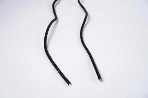 Two cut ends of a black electrical wire, exposing the inner metallic copper.. Stock Photos