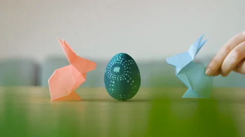 Two cute and funny paper Easter bunnies hopping to a blue decorated Easter egg. Stock Footage 149061325