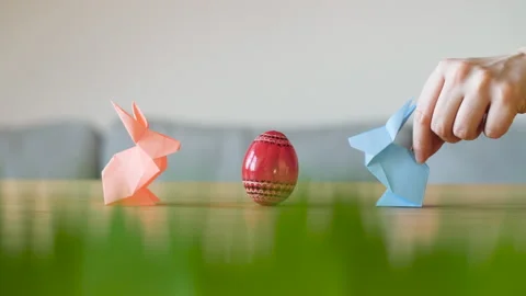Two cute and funny paper Easter bunnies hopping to red decorated Easter egg. Stock Footage 149068151