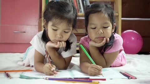 Two cute asian little girls having fun to paint with crayon together Stock Footage