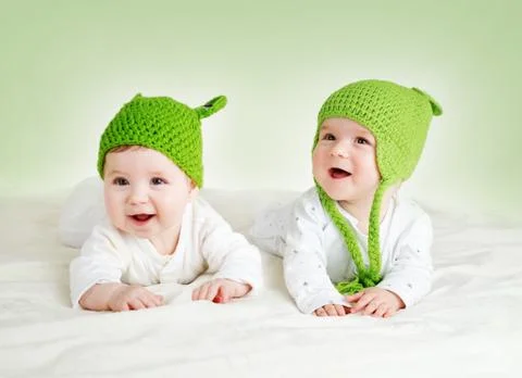 Two cute babies lying in frog hats on spft blanket Stock Photos