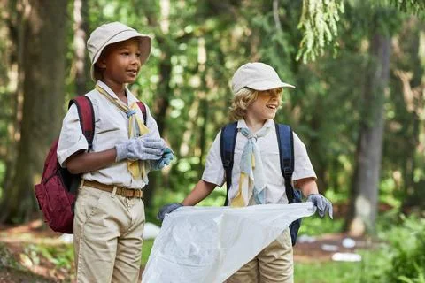 Two cute boy scouts helping clean forest and holding trash bag Foto stock