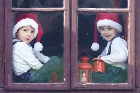 Two cute boys, looking through a window, waiting for santa Stock Photos