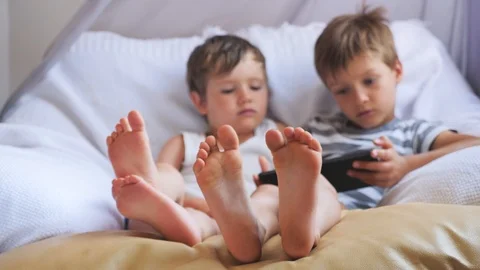 Two cute boys taking a rest at daytime. Focus on boys' feet. Stock Footage 97809387