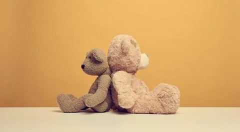Two cute brown teddy bears sitting on a yellow background, childrens toy Stock Photos