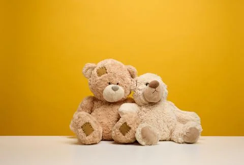 Two cute brown teddy bears sitting on a yellow background, childrens toy Stock Photos
