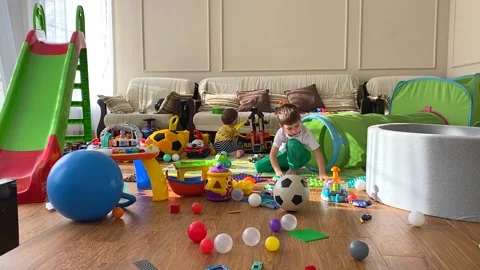 Two cute children are playing with toys in the children's room. A mess in the Stock Footage 171381080