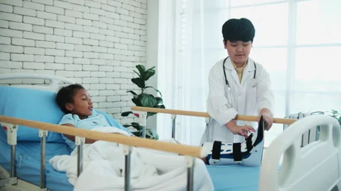 Two cute, diverse children role-playing as doctor and sick patient in uniform. Stock Footage 330984971