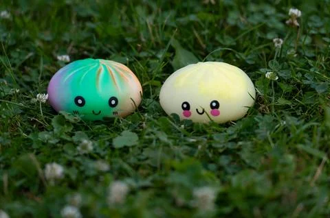 Two cute dumpling squishy stress toys sitting on lawn close-up Stock Photos