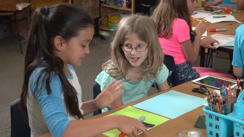 Two cute elementary school students (girls)  working together on a project Видео 99375713