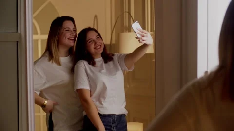 Two cute girlfriends take a funny selfie in a large mirror. Photos for social Stock Footage 243919337