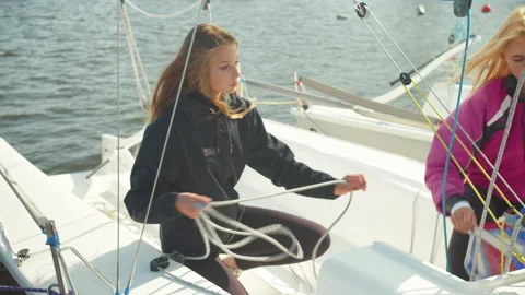 Two cute girls prepare a sailing yacht for departure at the pier on the river Stock Footage 145526342