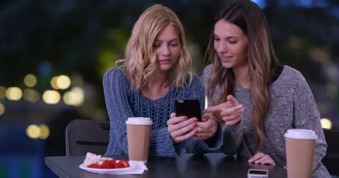 Two cute girls using cell phone to look at pictures outdoors in Paris France 写真素材