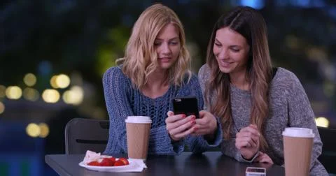Two cute girls using cell phone to look at pictures outdoors in Paris France 写真素材