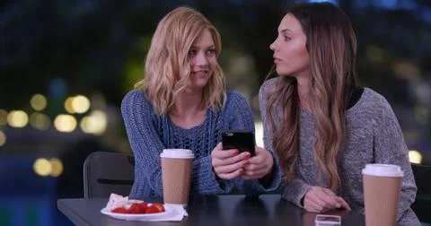 Two cute girls using cell phone to look at pictures outdoors in Paris France 写真素材