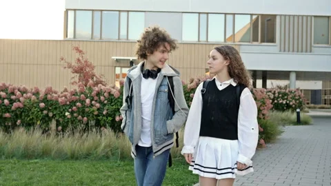 Two cute high school students, a guy and a girl, are walking around the Stock Footage 232592491