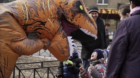 Two cute kids talking to person in t rex costume at sidewalk Stock Footage 84931018