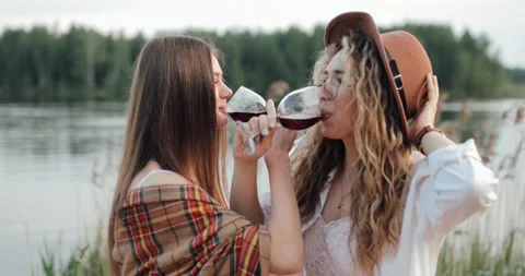 Two cute lesbians on the background of a lake drinking wine on the bruderschaft Stock Footage 132815242