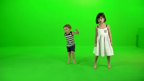 Two cute little kids dancing and playing around happily over a green screen. Stock Footage 99611713