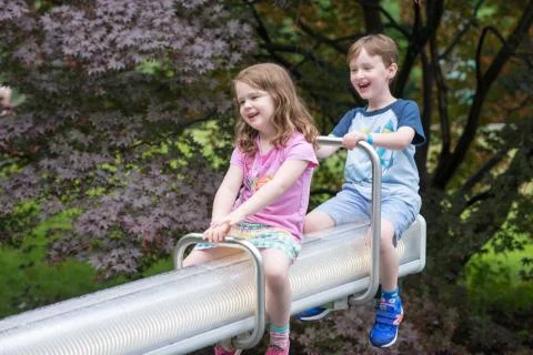 Two cute pre-school children sitting on a seesaw Stock Photos