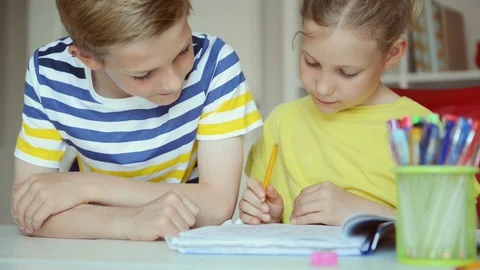Two cute schoolchildren boy and girl doing homework at home Stock Footage 111778612