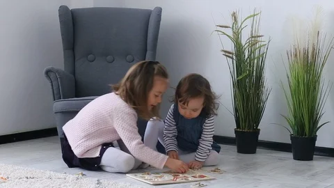 Two cute sisters make a puzzle with animals on the floor. 스톡 동영상 129557491